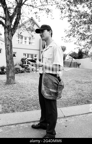 JOHANNESBURG, SÜDAFRIKA - 13. Mär 2021: Johannesburg, Südafrika - 11. September 2010: Post Mailman Hand liefert Post in einem wohlhabenden Vorort Stockfoto