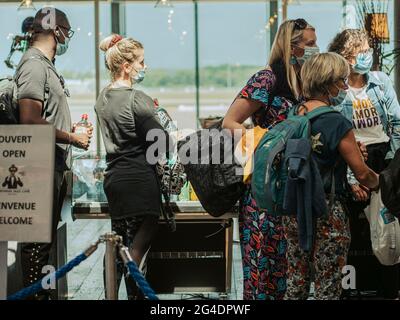 Passagiere stehen in einer Abflughalle am Flughafen in der Warteschlange. Die Passagiere, die alle maskiert sind, stehen in einer Abflughalle am Flughafen Genf in der Schlange. Stockfoto