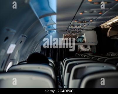 Innenraum von leeren Sitzen in einem Flugzeug. Nur wenige Passagiere sitzen während eines gesperrten Fluges und eines Corona-Virus-Reiseverbots im leeren Flugzeug. Stockfoto