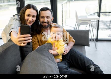 Glückliche Familie mit einem einjährigen Baby, das einen Videoanruf am Telefon hat Stockfoto