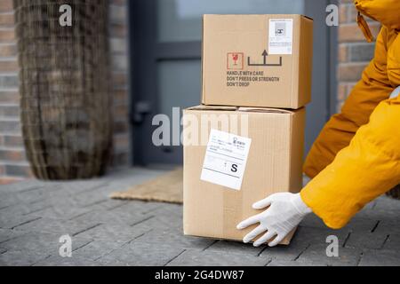 Courier legt Pakete auf die Veranda vor der Haustür, Stockfoto