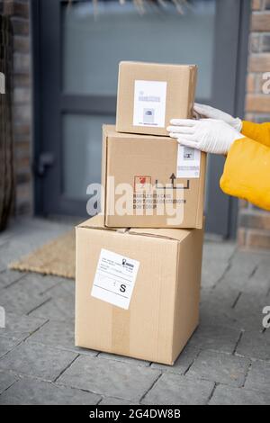 Courier legt Pakete auf die Veranda vor der Haustür, Stockfoto