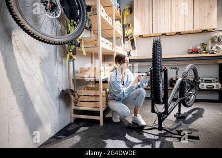 Handywoman pumpt Fahrradräder in der Werkstatt Stockfoto