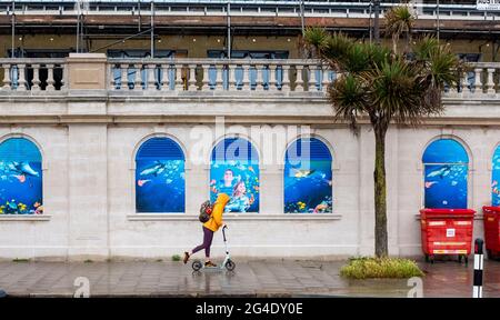 Brighton UK 21. Juni 2021 - starker Regen dämpft die Sommersonnenwende, während ein Motorroller-Fahrer heute entlang der Strandpromenade von Brighton fährt : Credit Simon Dack / Alamy Live News Stockfoto