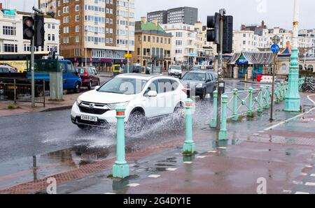 Brighton UK 21. Juni 2021 - der Verkehr spritzt durch Pfützen, während heute starker Regen die Sommersonnenwende an der Strandpromenade von Brighton dämpft : Credit Simon Dack / Alamy Live News Stockfoto