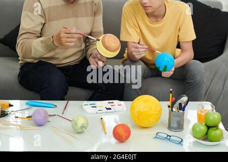 Vater und Sohn verbringen Zeit miteinander, sie verpaaren Kugeln mit verschiedenen Farben, um Sonnensystem Modell für die Schule zu machen Stockfoto