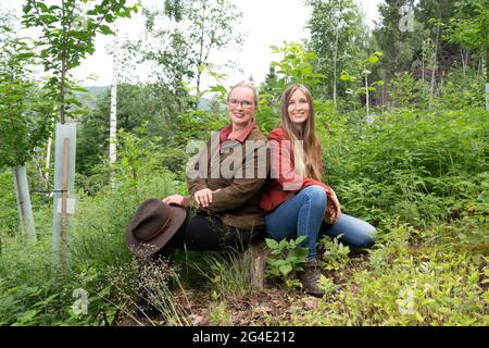 Liebstadt, Deutschland. Juni 2021. Bärbel Kemper (l.) und ihre Tochter Anna-Karina sitzen auf einem Baumstumpf im Bienenwald. Kemper wurde mit ihrem artenreichen Biotopverbund für den Deutschen Waldpreis nominiert. Der Preis zeichnet Personen aus, die sich besonders für den Forstsektor einsetzen. Quelle: Sebastian Kahnert/dpa-Zentralbild/dpa/Alamy Live News Stockfoto