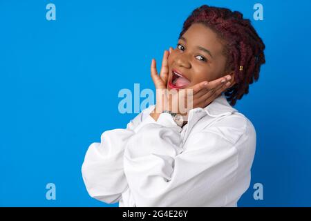 Erstaunt überraschte afroamerikanische Frau vor blauem Studiohintergrund Stockfoto