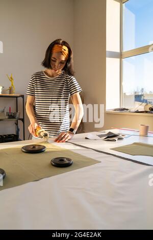 Schneiden und Nähen im Schneideratelier: Kanalisation junge Frau arbeitet mit Stoff in Design-Werkstatt-Studio Stockfoto