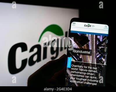 Person, die Mobiltelefon mit der Webseite des US-amerikanischen Lebensmittel- und Landwirtschaftsunternehmens Cargill Inc. Auf dem Bildschirm vor dem Logo hält. Konzentrieren Sie sich auf die Mitte des Telefondisplays. Stockfoto