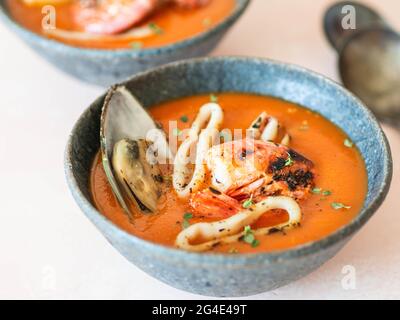 Tomatensuppe mit Meeresfrüchten in blauen Keramikschalen. Mediterrane Küche. Nahaufnahme. Selektiver Fokus. Stockfoto