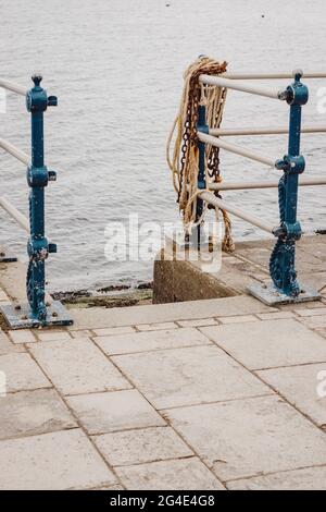 Strandweg mit Metallbarrieren, verwittertem Seil und Kette mit Blick auf das Meer. Stockfoto