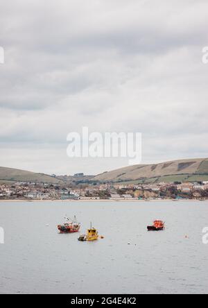 Fischerboote vertäuten im Hafen von Swanage, der vom Küstenpfad aus sichtbar ist, mit der Jurassic Coast dahinter. Stockfoto