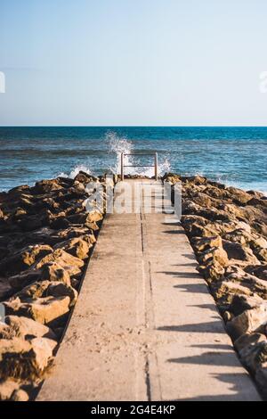 An einem sonnigen Tag planscht das Meer auf die Küstenverteidigung in Dorset, England, Großbritannien. Stockfoto