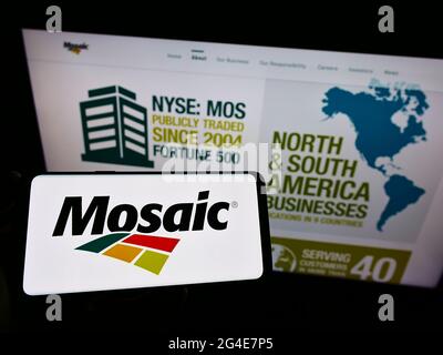 Person, die Mobiltelefon mit dem Logo des US-Düngemittelherstellers The Mosaic Company auf dem Bildschirm vor der Business-Webseite hält. Konzentrieren Sie sich auf die Telefonanzeige. Stockfoto