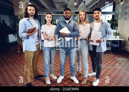 Gruppenportrait von fünf verschiedenen jungen Kollegen, die in einem stehen Zeile im Büro Stockfoto