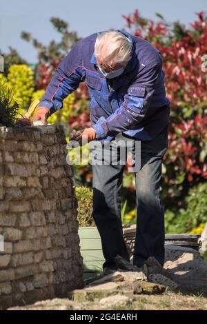 Älterer Mann, Baumeister Zementieren, Zeigen EINER rustikalen Steinwand mit EINEM Tuck Pointer Tool England Großbritannien Stockfoto