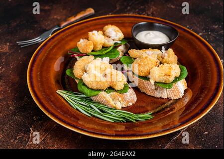 Sandwiches mit gebratenen Garnelen, Garnelen, Spinat und Mangold-Salat auf einem rustikalen Teller. Dunkler Hintergrund. Draufsicht Stockfoto