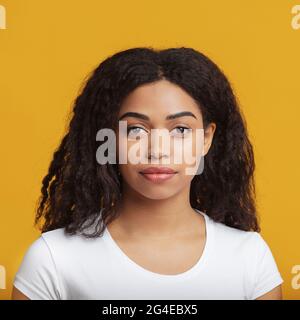 Natürliche Schönheit. Porträt einer jungen afroamerikanischen Frau mit schönen lockigen Haaren, posiert auf gelbem Hintergrund Stockfoto