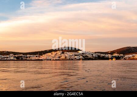 Naoussa Küstendorf auf der Insel Paros mit weißen kykladischen Häusern in rosa Sonnenaufgangsfarben und rosa Wolken am Himmel, am frühen Morgen in Griechenland. Stockfoto