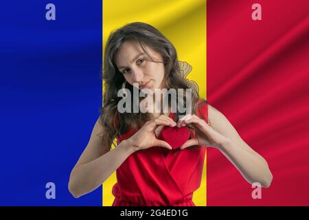 Ich Liebe Andorra. Ein Mädchen hält vor dem Hintergrund der Flagge Andorras ein Herz auf ihrer Brust in den Händen. Der Begriff des Patriotismus. Stockfoto
