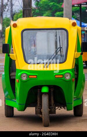 Grün und gelb umweltfreundliche elektronische Tuk Tuk Fahrzeug Auto Rikscha in Luang Prabang Laos Asien. Stockfoto