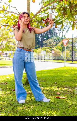 Junge Frau, die in einem Park an einem Videoanruf teilnimmt Stockfoto