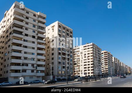 Straße von Hurghada Stadt in Ägypten. Wohngebäude im gleichen architektonischen Stil in einem Wohngebiet der Stadt neben einer lauten Straße. Stockfoto