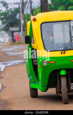 Grün und gelb umweltfreundliche elektronische Tuk Tuk Fahrzeug Auto Rikscha in Luang Prabang Laos Asien. Stockfoto