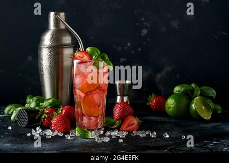 Glas Punsch und frische Zutaten für die Herstellung von Limonade, infundiert entgiftetes Wasser oder Cocktail. Erdbeeren, Limette, Minze, Basilikum, Eiswürfel und Shaker auf BL Stockfoto