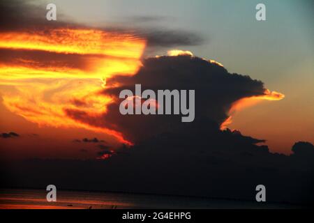 Wunderschöne Farben am Himmel, wenn die Sonne hinter einer großen Wolke untergeht Stockfoto