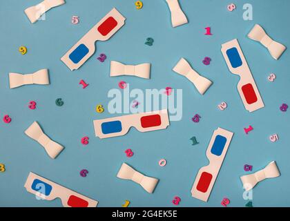 Flache Lay-Komposition mit 3D-Brille, Papierbändern und holzfarbenen Zahlen auf blauem Hintergrund. Draufsicht. Stockfoto
