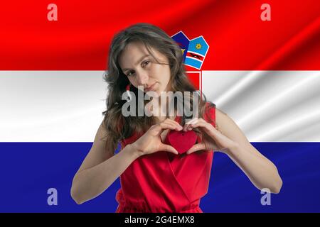 Ich Liebe Kroatien. Ein Mädchen hält vor dem Hintergrund der kroatischen Flagge ein Herz auf ihrer Brust in den Händen. Der Begriff des Patriotismus. Stockfoto