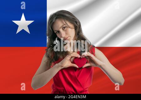 Ich Liebe Chile. Ein Mädchen hält vor dem Hintergrund der chilenischen Flagge ein Herz auf ihrer Brust in den Händen. Der Begriff des Patriotismus. Stockfoto