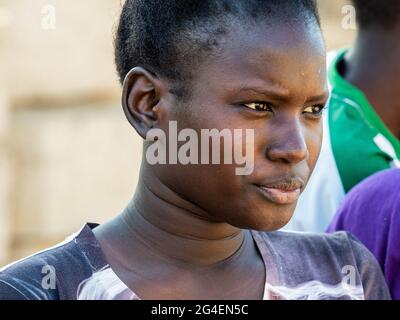 MBOUR, SENEGAL - JANUAR CIRCA, 2021. Nicht identifizierter Teenager mit trauriger Angst, der über die Lebensweise in einem armen afrikanischen Dorf nachdenkt. Stockfoto