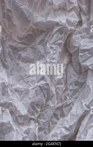 Weißer zerknitterter Papierhintergrund, Textur für Design. Vorlage zum Erstellen von Verpackungen. Vertikales Zuschneiden. Nahaufnahme. Stockfoto