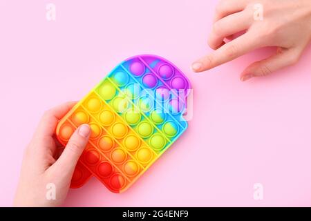 Bunte Antistress Sinnesspielzeug Fidget Push Pop es auf rosa Hintergrund, Draufsicht Stockfoto