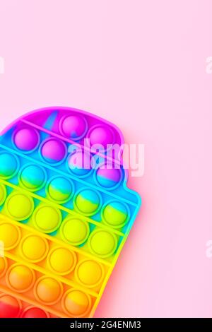 Bunte Antistress Sinnesspielzeug Fidget Push Pop es auf rosa Hintergrund, Draufsicht Stockfoto