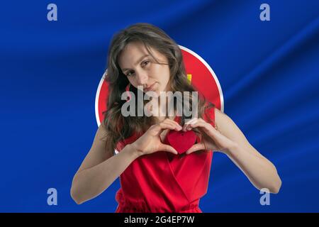 Love Association of Southeast Asian Nations. Ein Mädchen hält ein Herz auf ihrer Brust in ihren Händen vor dem Hintergrund der Flagge der Association of South Stockfoto