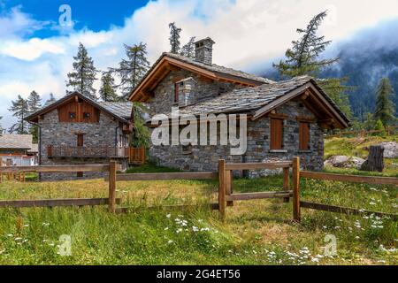 Steingasthäuser auf grüner Wiese in den Bergen im Piemont, Norditalien. Stockfoto