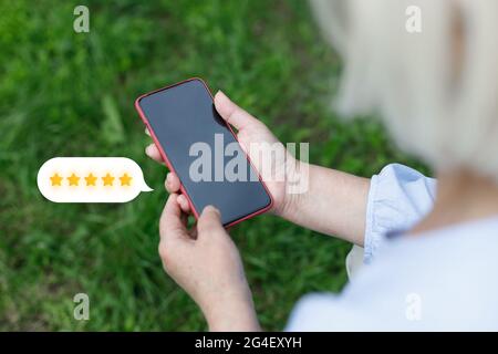 Person Hand mit Mobiltelefon mit Symbol zwei Sterne-Symbol, um die Bewertung des Unternehmens zu erhöhen, Kundendienst Konzept Stockfoto