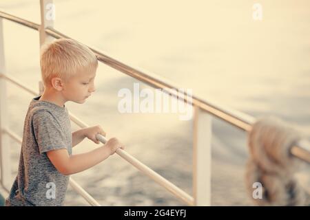 Ein kleiner Junge an Bord eines großen Schiffes Stockfoto