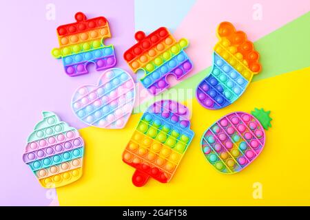 Bunte Push Pop IT Bubble Sensory Fidget Spielzeug in verschiedenen Formen, auf buntem Hintergrund Stockfoto