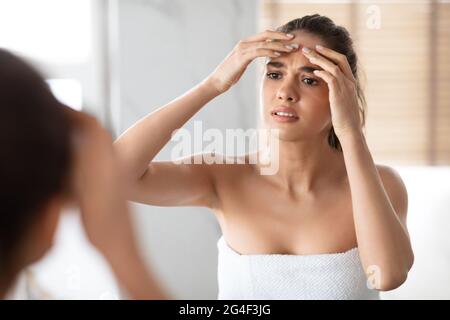 Frau Quetscht Pickel Auf Die Stirn Und Schaut Im Badezimmer Im Spiegel Stockfoto