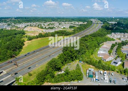 Asphaltstraße durch kleine typische Siedlung und grüne Bäume am Horizont live Luftaufnahme Stockfoto