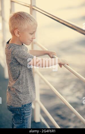 Ein kleiner Junge an Bord eines großen Schiffes Stockfoto