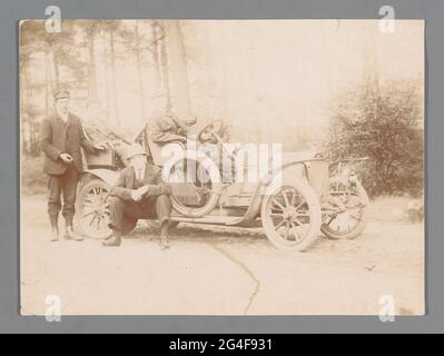 Fünf unbekannte Männer um ein Auto in einem Wald herum. . Stockfoto