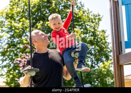 Vater spielt mit seinem 3-jährigen Sohn auf dem Spielplatz Stockfoto