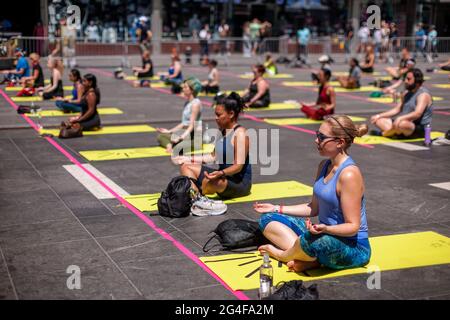 Sozial ferne Yogapraktiker packen den Times Square in New York ein, um am ersten Sommertag, Sonntag, 21. Juni 2021, Yoga zu praktizieren. Die jährliche Sonnenwende am Times Square, „Mind over Madness“, gesponsert von Ayrie, dem Generalkonsulat von Indien, New York und SmartWater, dehnt die Fähigkeit der Yogis aus, den Lärm und das visuelle Durcheinander, das sie an der Kreuzung der Welt umgibt, zu blockieren. Der erste Sommertag wurde von den Vereinten Nationen zum Internationalen Tag des Yoga erklärt. (ÂPhoto von Richard B. Levine) Stockfoto