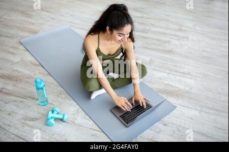 Millennial indische Frau, die vor dem inländischen Training Online-Sportvideos auf dem Laptop ansieht, oben. Aktiver Lebensstil Stockfoto